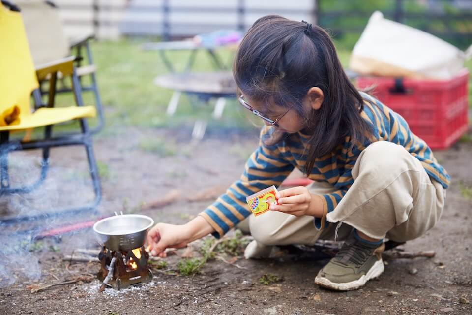 焚き火でお湯を沸かしている子ども