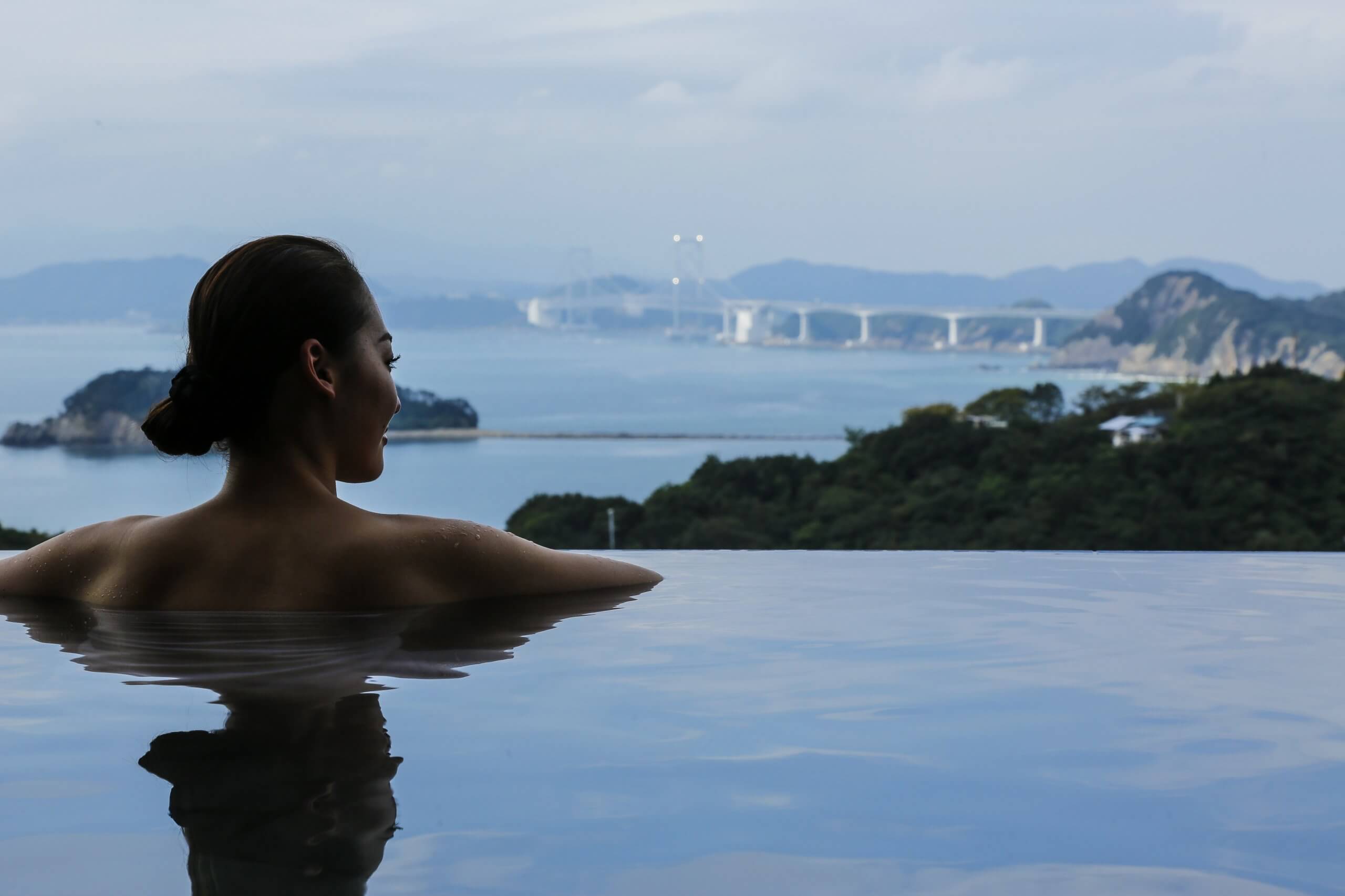 海の見える温泉を楽しむ女性