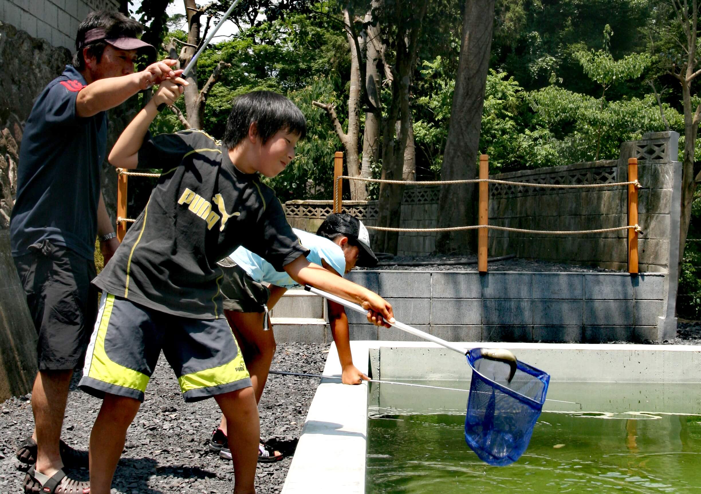 網と竿を持って魚釣りを楽しむ男の子