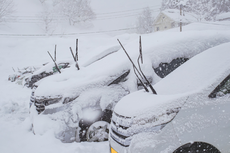 大雪を被ったクルマがワイパーを立てた状態で駐車している光景
