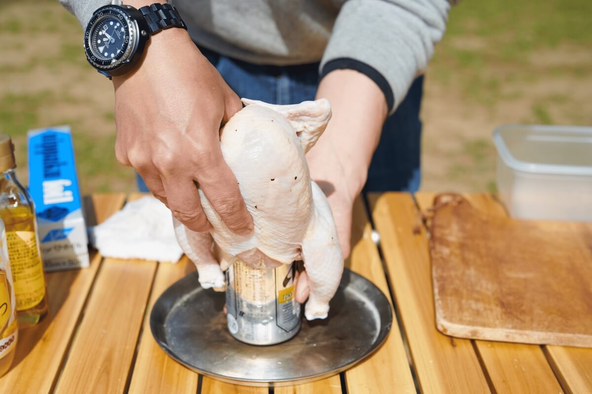 ビア缶に丸鶏を差し込んでいるようす