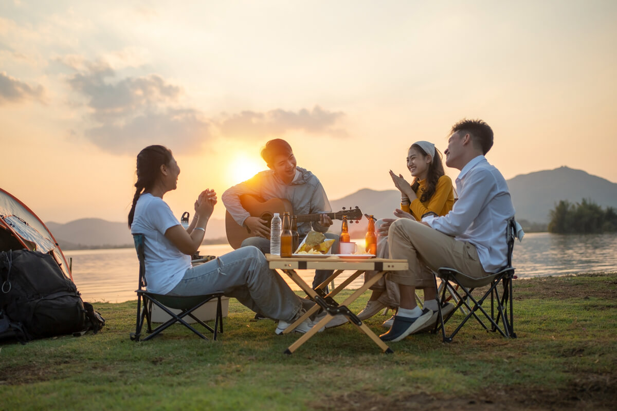 キャンプでの夕暮れのなか、仲間と団らんしているようす