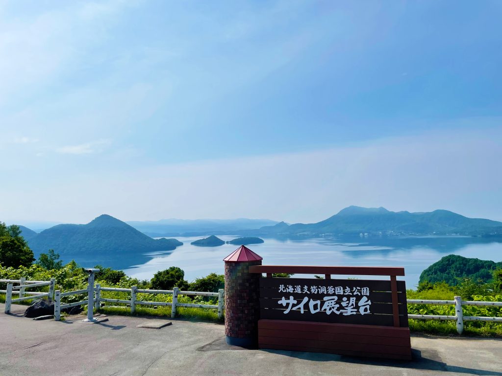 「サイロ展望台」と書かれた看板の向こうに、湖と島々、そして山々が見える。