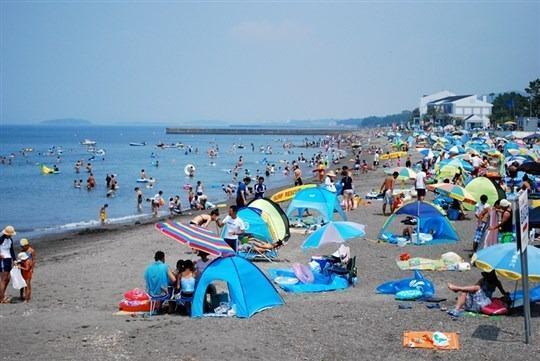 大勢の人々が、テントやパラソルを広げて海水浴を楽しんでいる。