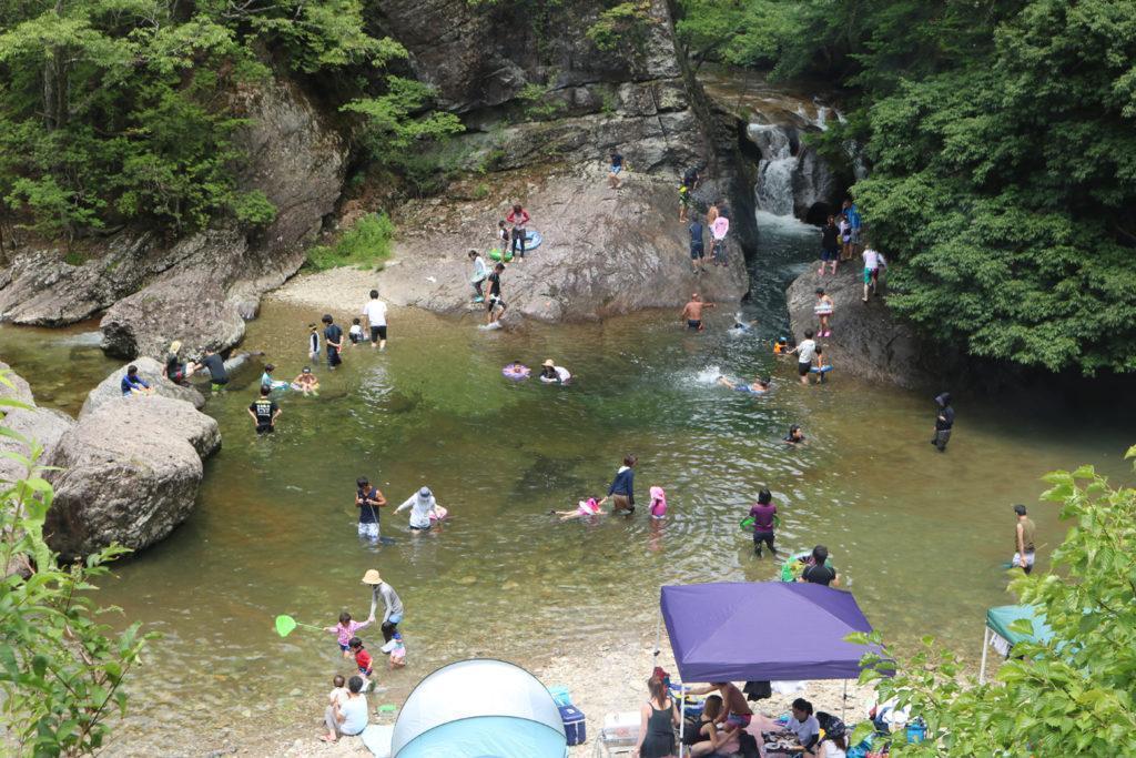 渓谷の川で、多くの人々が水遊びを楽しんでいる。