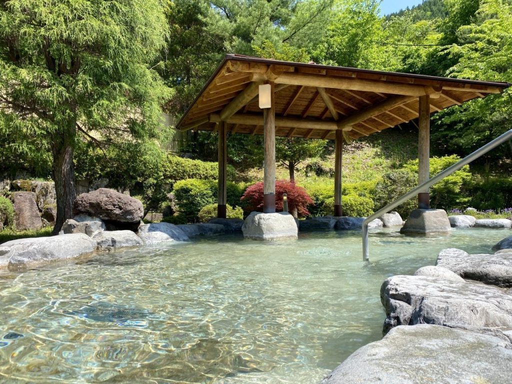 木々と岩に囲まれた、屋根付きの広い露天風呂。