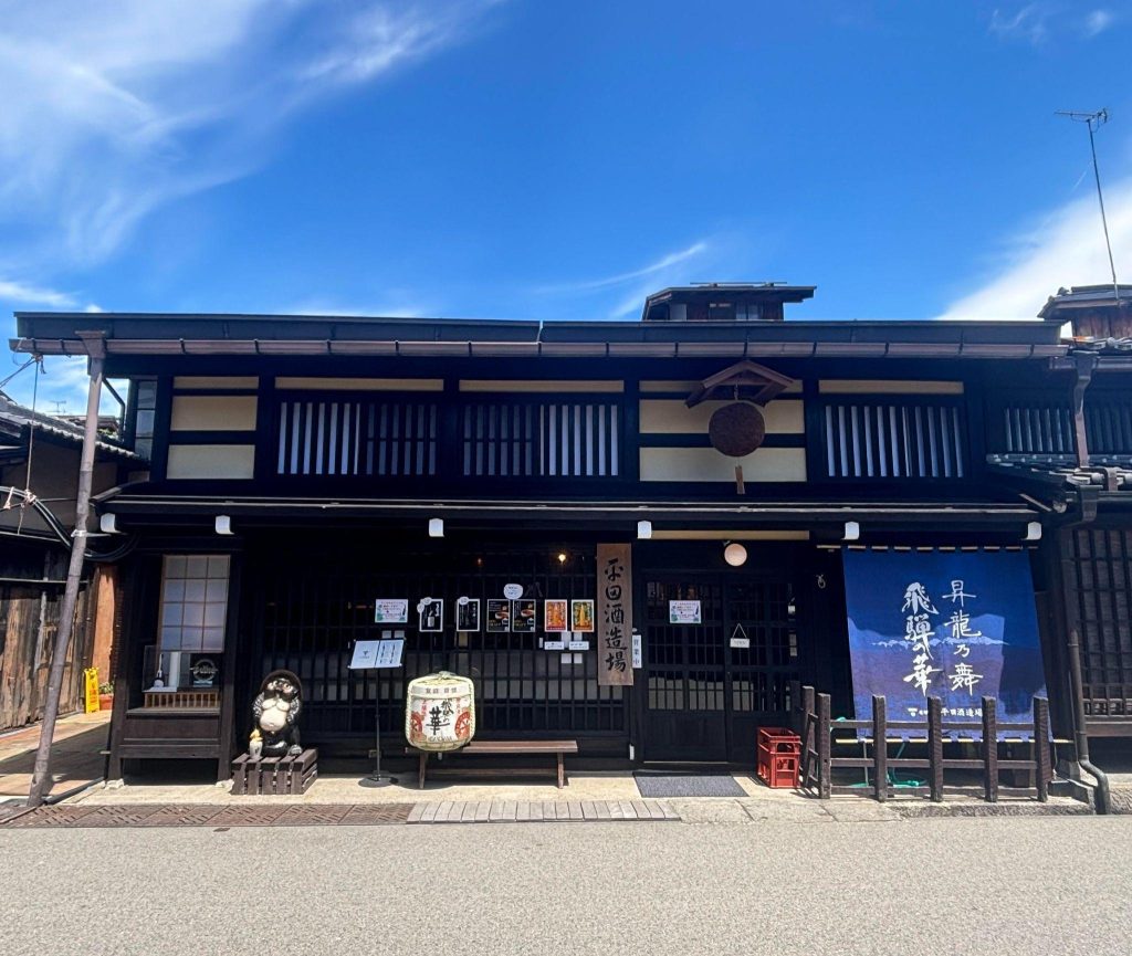 青い空の下、黒い瓦屋根の日本家屋が建っている。
