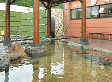 湯気が出ており、竹の柵がある屋外の温泉。