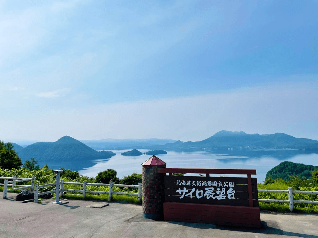 「サイロ展望台」と書かれた看板の向こうに、湖と島々、そして山々が見える。