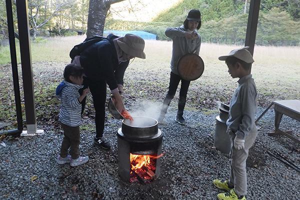屋根の下で、かまどを使って調理をする家族。