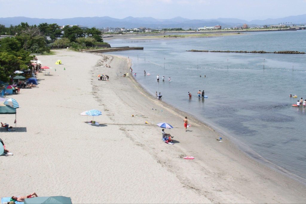 晴れた日に、多くの人々が海水浴を楽しむビーチ。