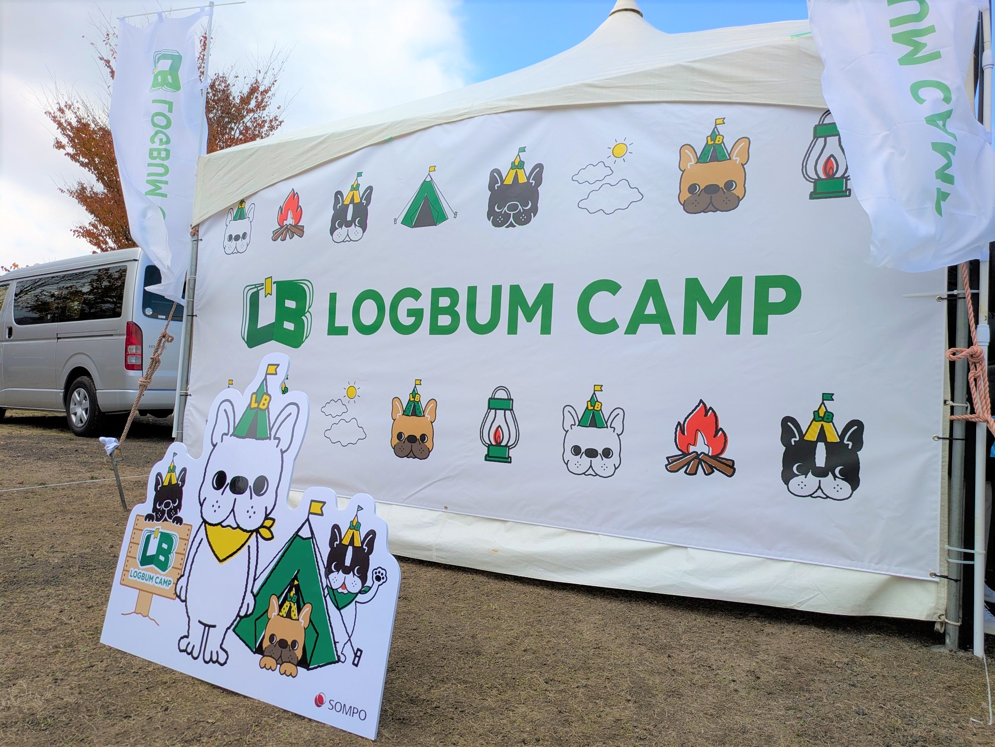 「LOGBUM CAMP」と書かれたブースの看板。フレンチブルドッグをモチーフにしたキャンプ関連のイラストが描かれている。