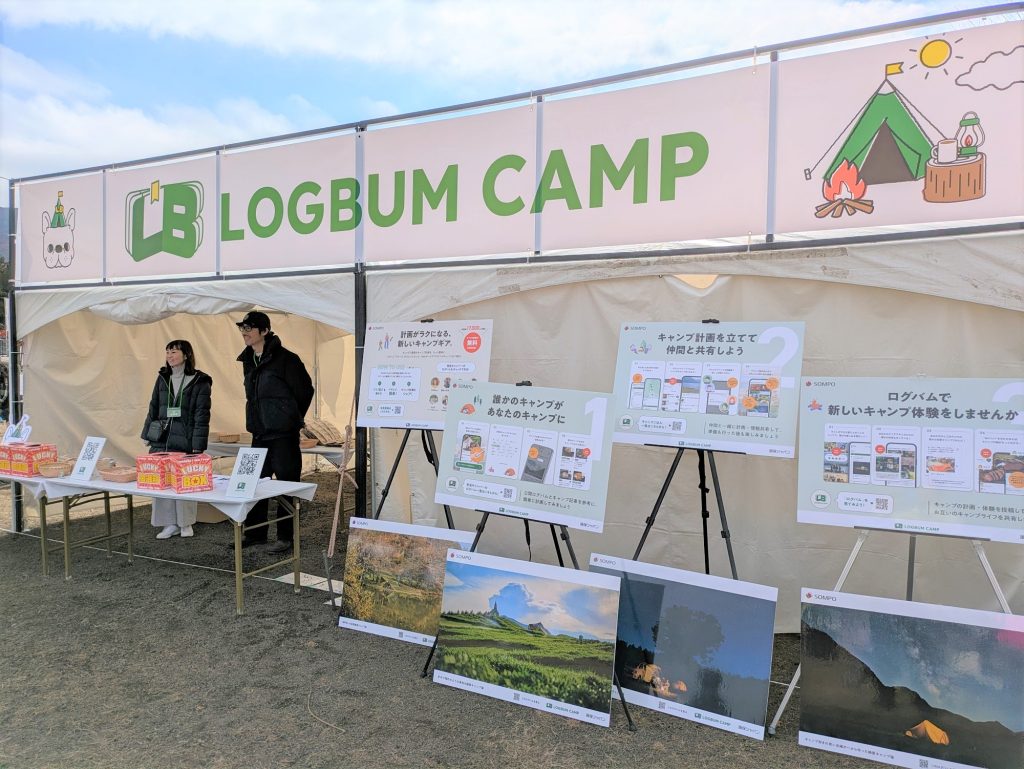 「LOGBUM CAMP」のブース。スタッフ2人が立っており、キャンプに関する説明パネルが展示されている。